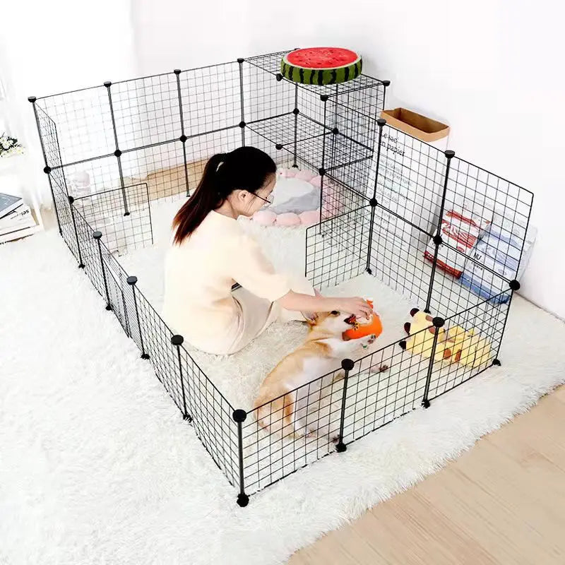 Person interacting with a dog inside a black metal pet pen on a white floor.